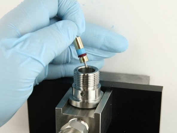Put the poppet needle, with the point down, at the top of the valve body.