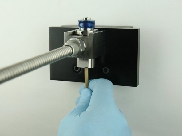 With the dowel, push the poppet stem point flush with the bottom of the bore.