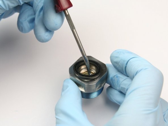 Remove the wiper from the top of the bearing half of the swivel housing with a pick.