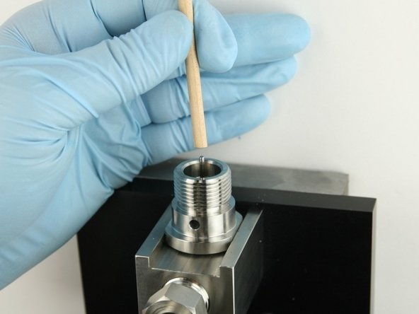 Use the dowel to push the poppet needle down until the back-up ring is flush with the top of the bore.