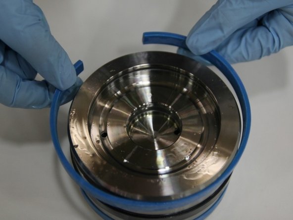 Put the first wear ring onto the bottom groove of the piston.