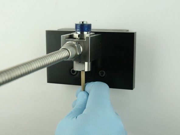 With the dowel, push the poppet stem point flush with the bottom of the bore.