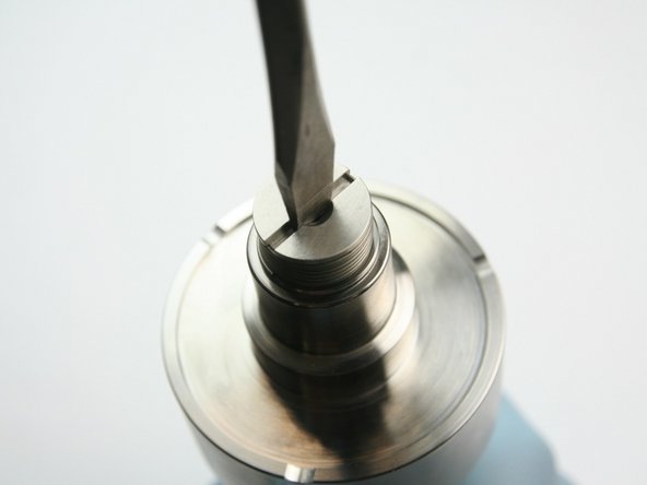 Tighten the poppet retainer into the sealing head body with the flat head screwdriver.