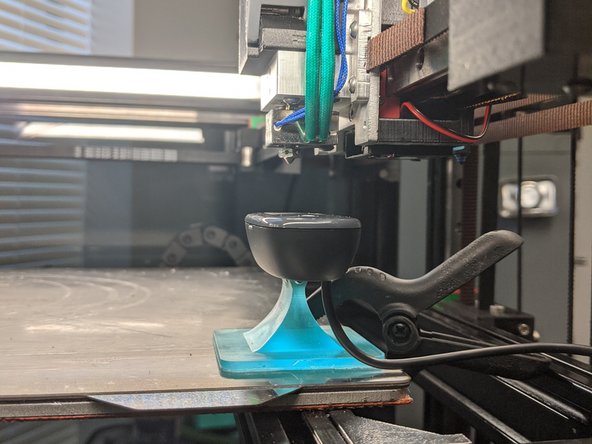 Mount webcam somewhere fixed on the bed using gluestick/double sided tape OR on the frame in a spot where the nozzle of the tool can be positioned over the lens.