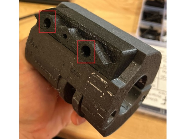 With your assembled and locked grip, take the TPU adapter piece and align it as seen in the picture. Take the 2 M4 x 30 screws and screw them into the holes shown in the picture.