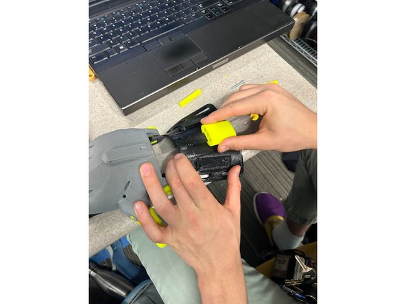 Slide the Tensioner (I) onto the gauntlet with the square holes facing towards the hand, and the circular holes facing the other way. You will know the tensioner is secure when it clicks in to place.
