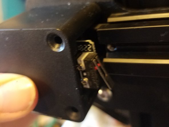 Hold the motor and the black cover steady, with the end stop facing inwards towards the nozzle carriage.