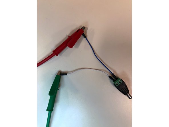 Put a male to male jumper wire into each end of the DC barrel plug, and then attach the j. wire from the positive end, denoted with a positive sign, to the positive alligator clip from the bench power supply and the negative j. wire to the negative alligator clip.