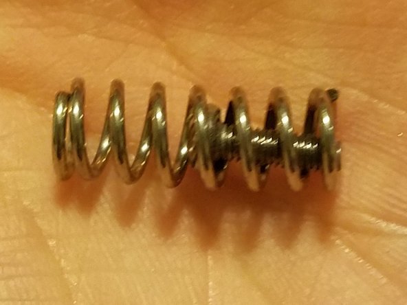 Place one of the hex screws you removed from the stock motor frame inside of the new spring, then compress it and slide it into position between the idler arm and frame.