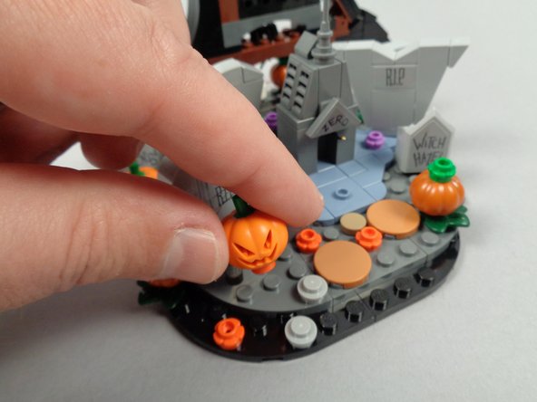 As shown in the first photo for this step, remove the front pumpkin and its orange flower plate from the base.