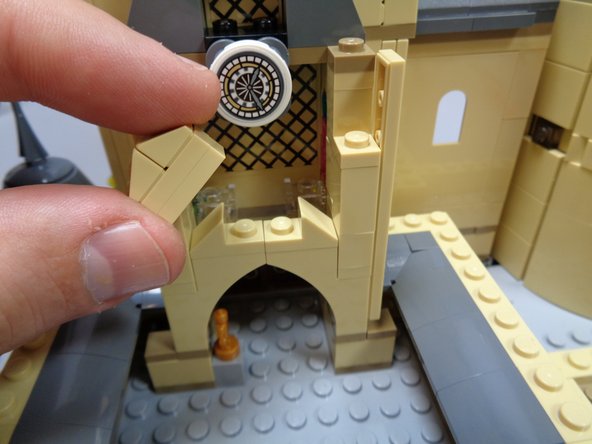 As shown in the third photo, use a LEGO brick separator to remove the bottom 1x2 tan plate from the center arch assembly.