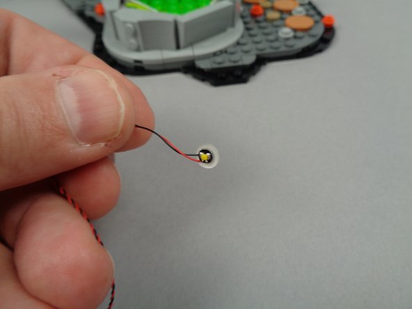 As shown by the green lines in the third photo for this step, attach the LED light to the outer town hall wall with its wires facing upward.