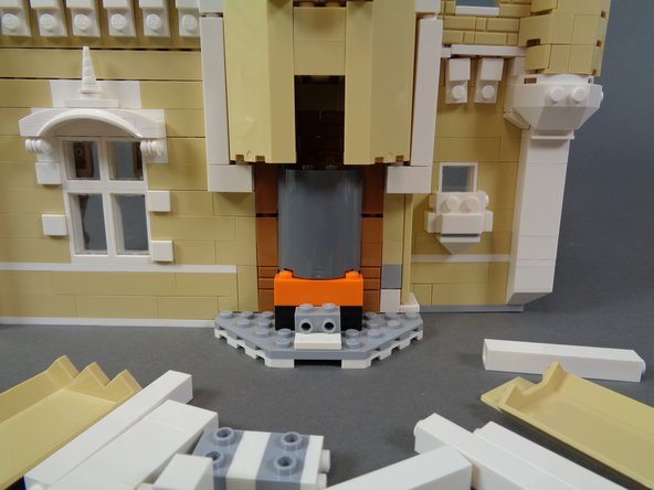 As shown in the photos for this step, use a brick separator to begin disassembling the front section of the castle behind the kitchen stove.