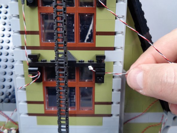 To do this, pass the wire through the top of the fourth window frame and to the left, as shown in the second and third photos for this step.