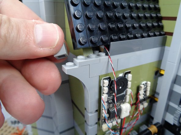 As shown in the photos for this step, remove several pieces from the back side of the mansion wall.  This is to make room for passing the wire for the green LED light.