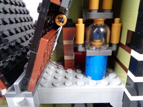 The second photo for this step shows the light wire passing out the back of the mansion.  Pull the wire all the way through, so the wire inside the attic is hidden as shown in the third photo.