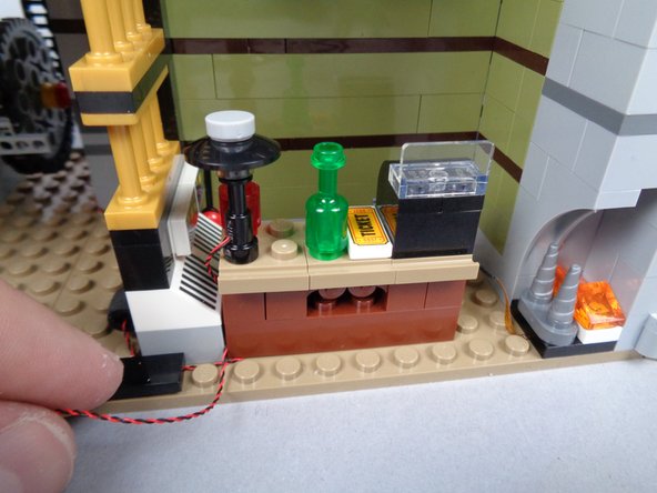 As shown in the photos for this step, re-attach the front desk and the minifigure.