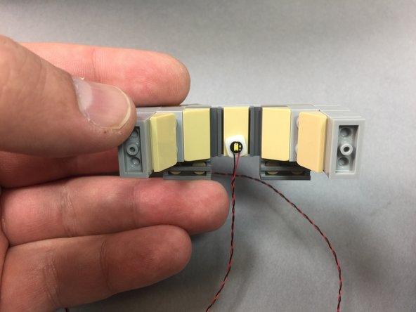 As shown in the first photo, take a small sticky square from the Main Control and Connecting Parts bag and use it to attach one LED light to the top of the door frame you removed in the previous step.
