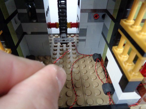 As shown by the yellow rectangle in the third photo for this step, feed the lamp LED Light wire through the holes in the Technic brick and wrap the wire several times to hold it in place.  Make sure to keep the wires away from any gears.