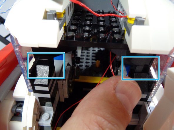 As shown by the two blue rectangles in the first photo for this step, finish re-attaching the rear roof section by re-connecting the two black arches at the far rear of the Ecto-1.