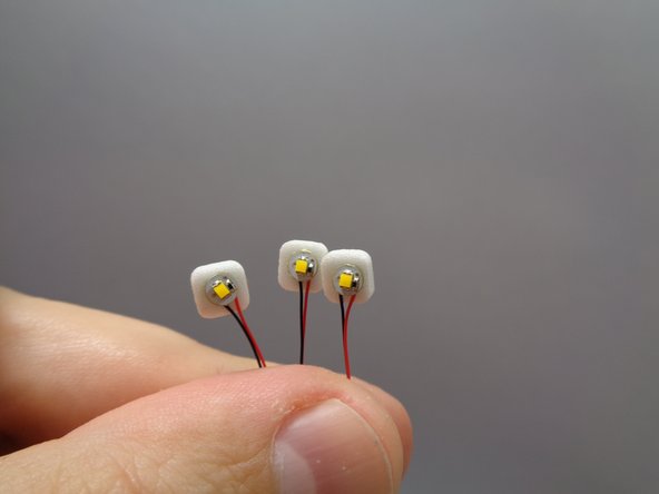 Take three warm white lights from Bag 10 and attach small sticky squares to the back of each as shown in the first photo.