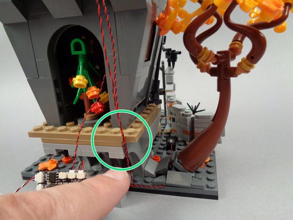 As shown by the green circle in the photo for this step, make sure the two second-floor light wires pass through the side of the back plate in Jack's house.  This will ensure the wires cannot be seen through the front door.