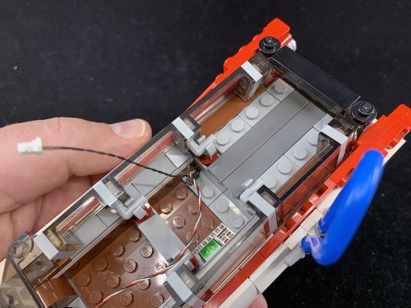 As shown in the three photos for this step, re-attach the side windows, dark bluish gray tiles, and while wheel well cover you removed in earlier steps.