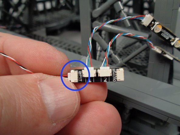 As shown by the blue circle in the second photo for this step, connect the end of the control cable coming from the first adapter board to the INPUT plug on the second adapter board.