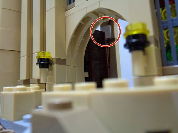 Hold the wires in place with one hand, remove one side of the protective tape on the sticky square, then press on top of the wires to hold them in place.  The red circle in the second photo shows how the sticky square holds the wires against the wall.