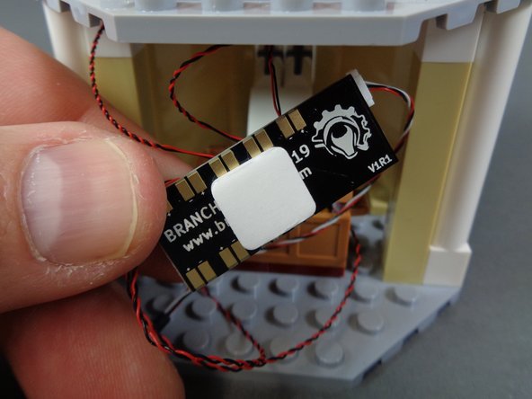 As shown in the photos for this step, use a large sticky square to mount the BRANCH09X adapter board to the ceiling of the lower room.