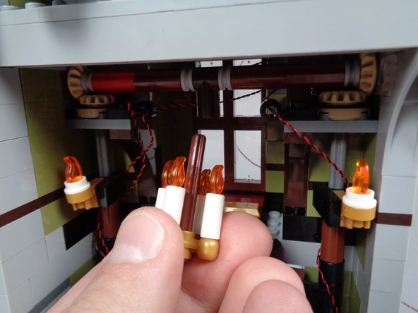 As shown in the photos for this step, remove the chandelier from its holder, and remove the four candles from the 4-hole gold base.