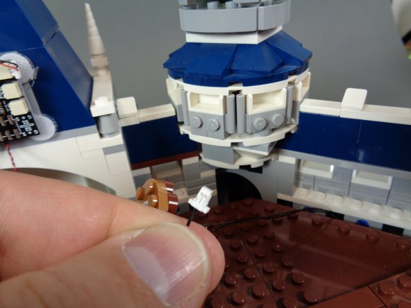 As shown in the photos for this step, take the black 2-wire power cable you ran from under the castle in Step 40 and connect it to one of the POWER plugs on the TRUNK08 master controller.