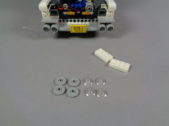As shown in the second photo for this step, remove the silver and transparent pieces from the white plates, so the headlights are fully disassembled.