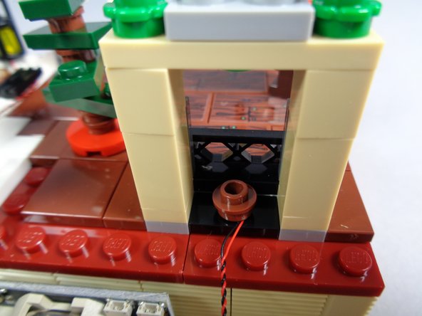 As shown in the first photo, carefully press the round brown 1x1 plate back into place in the fireplace.  The orange Pico LED light should be underneath the brown plate.