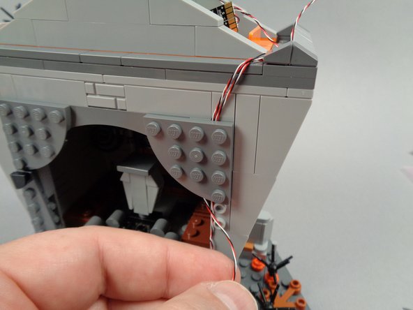 As shown by the photos for this step, re-attach the curtain pieces to the back of the town hall.  This will hold the two control wires in place.