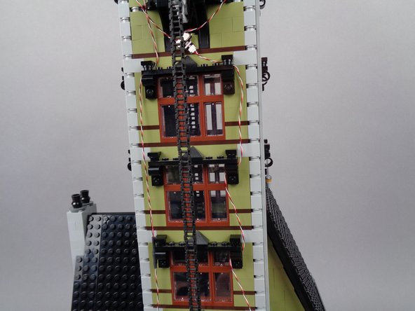 Continue routing the light strip wire downward as shown in the photos for this step, looping the wire through window frame parts as you go.