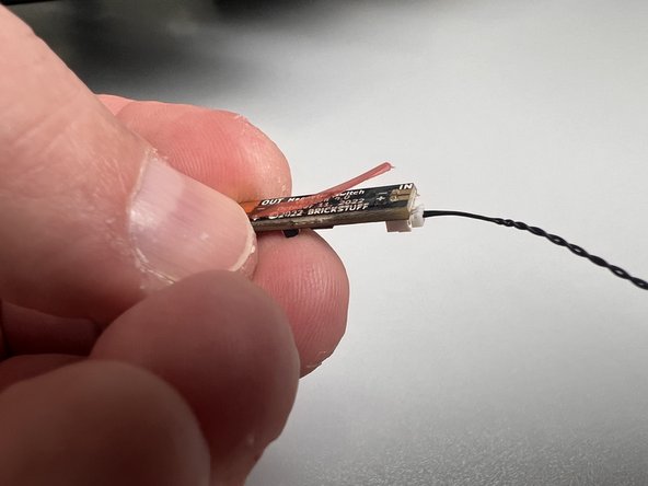 There is a thin adhesive film on the back side of the magnetic switch circuit board.  Carefully remove the red strip covering the adhesive, as shown in the second photo.