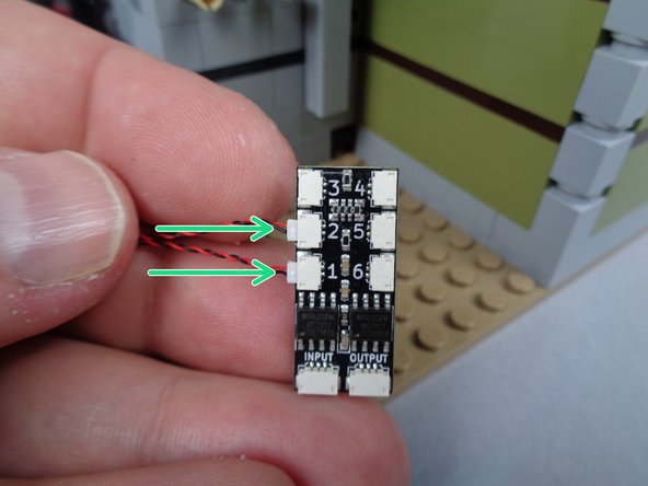 As shown in the second photo for this step, use one of the LEGO tiles to hold the two candle light wires in place.