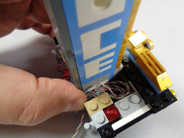 The first and second photos for this step show excess wire being coiled up in the open space inside the base.