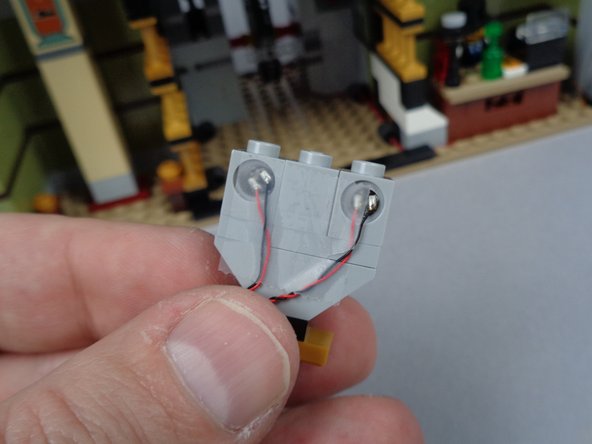 The third photo for this step shows the two red LED lights mounted in the back side of the eyes (held in place with transparent tape).