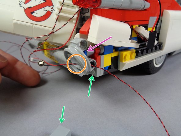 As shown by the green arrows in the first photo for this step, remove the brick just below the round tail light frame.  This will allow you to angle the round frame slightly outward (purple arrow).