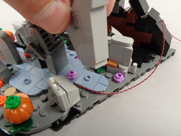 As shown in the first photo for this step, remove the large R.I.P. tombstone to make room to run the LED light wire.