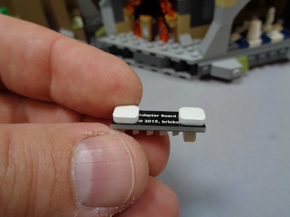 As shown in the second photo, take the BRANCH15 adapter board from Bag 9 and attach two small sticky squares to the back.  Leave the backing on the squares after attaching.