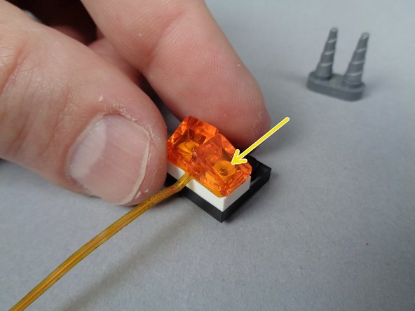 As shown by the blue arrow in the second photo, make sure the LED light is positioned roughly in the center of the LEGO stud after you have re-attached the transparent orange slope.
