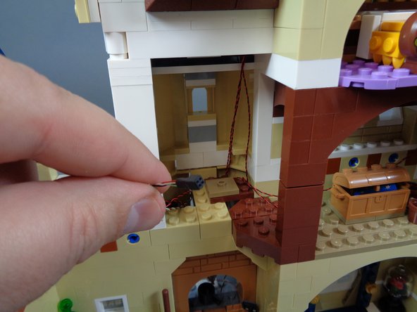 As shown by the photos in this step, take the end of the wire with the black &quot;female&quot; connector (without gold pins) and feed it up through the spinning room and through the top of the top open section as shown in the third photo.