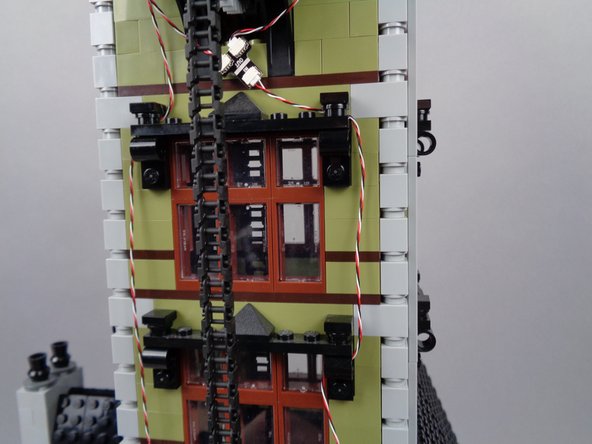 Continue routing the light strip wire downward as shown in the photos for this step, looping the wire through window frame parts as you go.