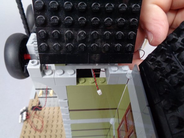 As shown in the first photo for this step, pass the wire for the second green LED light through the gap in the wall.