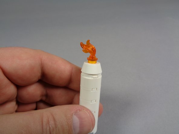 The tiny LED light should fit underneath the round transparent orange plate, under the flame with the clipped pin.