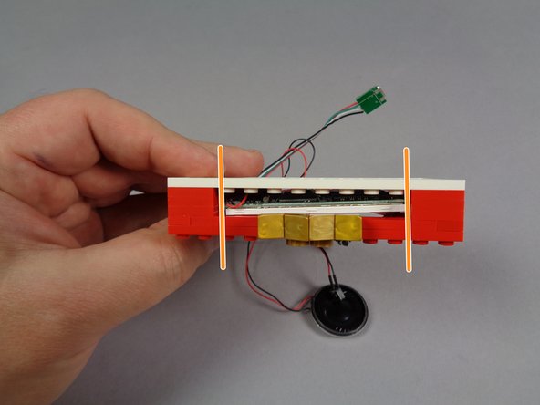 As shown by the blue circle in the first photo, all of the wires from the video player should be coming out the bottom of the frame, and should not be sitting on top of any LEGO® studs that might pinch the wires.