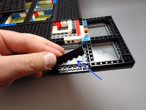 As shown by the blue arrow in the second photo for this step, remove the black 1x6 brick from the front of the foot assembly.